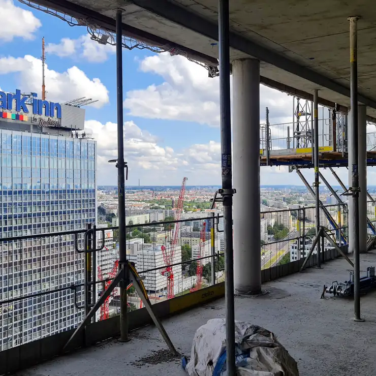 Blick aus einem Rohbau auf Hochhäuser am Alexanderplatz, im Vordergrund ein Kamerastativ