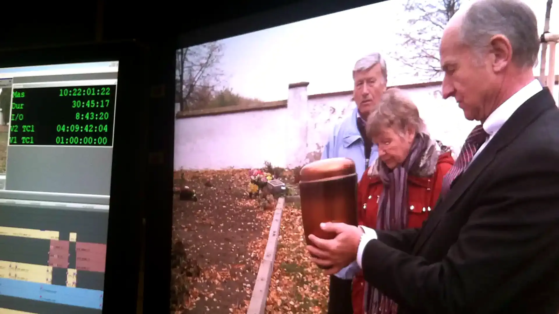 Zwei Männer mit einer Urne auf einem Feld